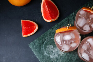 Glasses of tasty grapefruit margarita on dark background