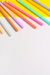 Colorful markers and blank paper sheet on color background