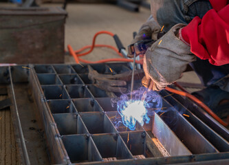 Worker welding steel grill pipe cap in factory.