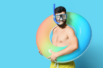 Young man with inflatable ring and snorkeling mask on color background - obrazy, fototapety, plakaty