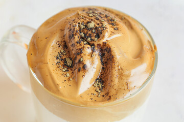 Glass cup of tasty dalgona hojicha latte on light background, closeup