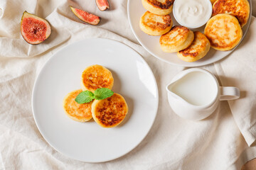 Plates with cottage cheese pancakes and milk on table