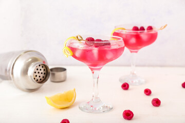 Glasses of tasty cosmopolitan cocktail on light background
