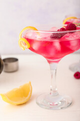 Glass of tasty cosmopolitan cocktail on light background, closeup