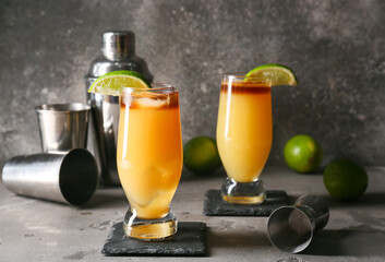 Glasses of tasty mai tai cocktail and shaker on grunge background