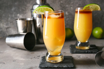 Glasses of tasty mai tai cocktail and shaker on grunge background