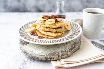 Protein pancakes topped with banana, syrup and glazed pecans. Healthy diet flapjacks. 