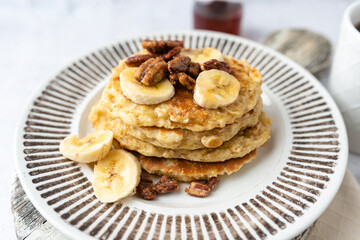 Protein pancakes topped with banana, syrup and glazed pecans. Healthy diet flapjacks. 