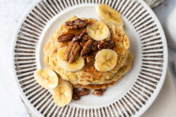 Protein pancakes topped with banana, syrup and glazed pecans. Healthy diet flapjacks. 