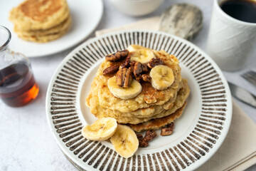 Protein pancakes topped with banana, syrup and glazed pecans. Healthy diet flapjacks. 