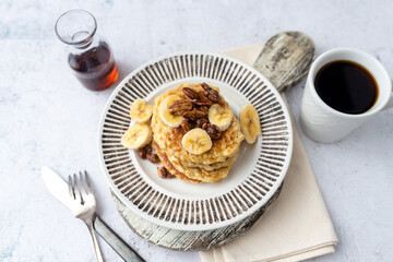 Protein pancakes topped with banana, syrup and glazed pecans. Healthy diet flapjacks. 
