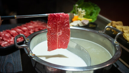 Beef raw meat hold with chopsticks. Hotpot with a brass pot in China