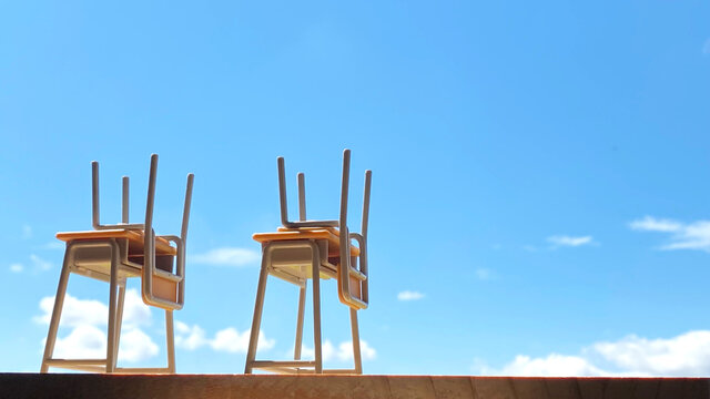机の上に椅子を押せた2つのスクールデスクと青空_右空間