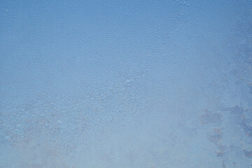 Frozen window texture. Ice-covered glass surface. Abstract winter blue background, wallpaper.