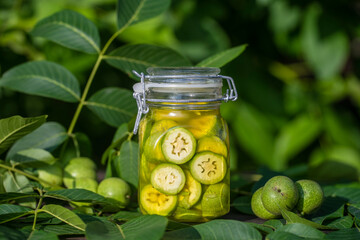 Sliced unripe walnuts in alcohol in a jar, to prepare homemade tincture, close up