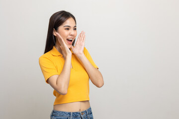 Excited asian woman shout out loud wow with hands on isolated background. Happy shocked face female wow promotion advertising concept. Joyful teenage girl in yellow shirt standing in white room. - obrazy, fototapety, plakaty