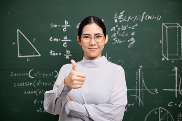 Young asian teacher woman teaching showing thumbs up and video conference with student looking camera. Female teacher training the mathematics in classroom blackboard from online course.