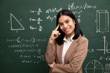 Young asian teacher woman standing looking at camera and video conference with student. Female teacher training the mathematics in classroom blackboard from online course.