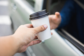 Drive thru coffee. Young buying a cup of hot coffee while driving the vehicle. Take a break for a...