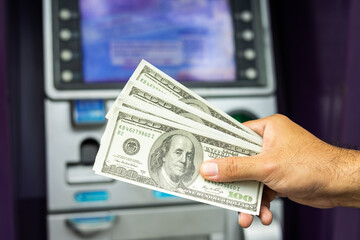 Young man take the money from atm machine. Business man hand put the credit card and password into...