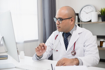 Doctor talks to patient via online video conferencing looking at screen. Explain about taking medications to treat illnesses and note the report.