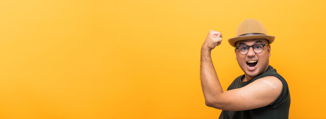 Vaccinated asian funny man showing arm after coronavirus Vaccination isolated yellow Background. Indian man getting a vaccination covid-19 immunization