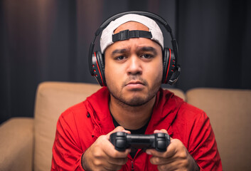 Sadness gamer man holding joystick. He lose in the game. Missed the chance to become a champion in tournament. Young indian playing video game online at home.