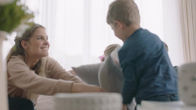 happy family having pillow fight mother and father enjoying playing with children at home having fun together on weekend 4k footage