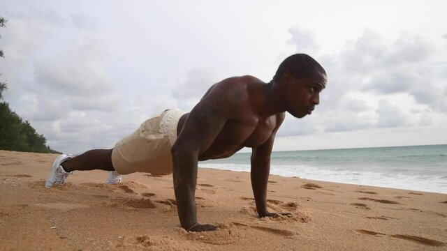 African American sport guy working out on the beach with a naked top