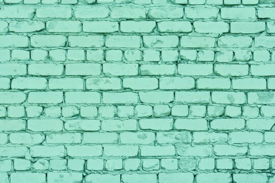 Mint green painted old rough brick wall. Pastel teal color texture. Shabby block pattern. Abstract background