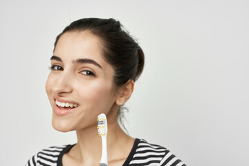 brunette in a striped t-shirt toothbrush in hand isolated background