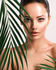 Young beautiful woman with green leaves near face and body. Skin care beauty treatments concept. ...