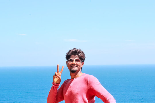 the person standing and making gesture in front of the sea 