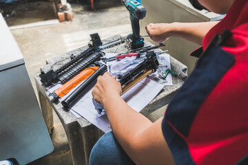 A technician man is repairing the drum of laser printer with specialized technical tools.