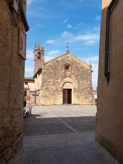 View from a Narrow Street in front of the Bell tower and the Church of Santa Maria Assunta in Piazza Roma in Monteriggioni, Siena - Italy