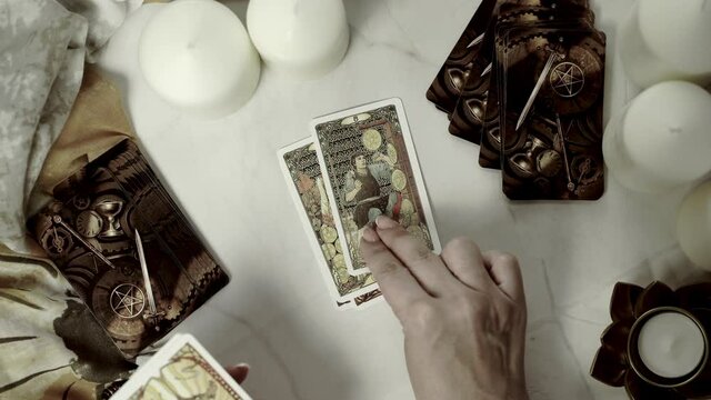 Tarot card reader arranges cards in a card spread.Fortune-telling on traditional tarot cards on the table with a candle. Selective focus.
