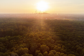 Drone view over forest and trees and an industrial area during the sunset in the ruhr area in...