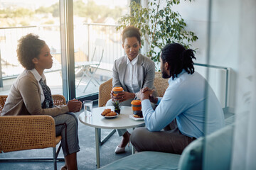Fototapeta premium African American businesswoman communicates with her coworkes during coffee break at work.