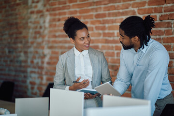 African American businesswoman and her colleague communicate while working at corporate office.