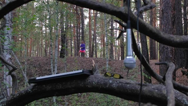 microphone and synthesizer in the summer forest at old tree on background of funny guy who is engaged in kung fu in colored clothes.