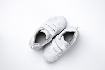 top view two white teen sneakers with velcro located diagonally isolated on a white background.