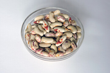 Colorful beans in a glass bowl, white background