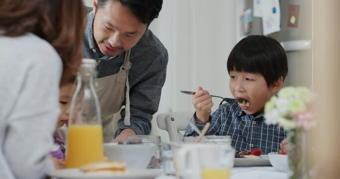 happy asian family eating pancakes for breakfast children enjoying healthy homemade meal with parents on weekend morning in kitchen 4k footage
