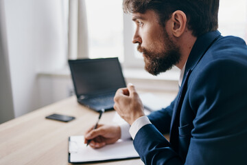Fototapeta premium bearded man sitting at a desk in front of a laptop finance technologies