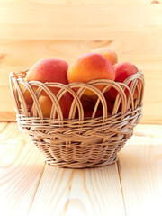 Ripe apricots in a wicker basket on a wooden table