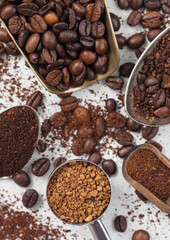 Ground and bean coffee and freeze dried instant coffee granules in various spoons and scoops on white background. Macro
