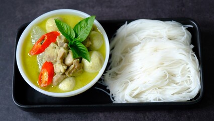Top view green curry chicken and fish ball with rice noodle (vermicelli) on black  background.