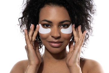Beautiful black woman with a smooth skin applying adhesive under-eyes patches for dark circles