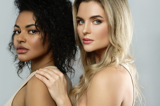 Portrait of Caucasian and African American women on gray background.