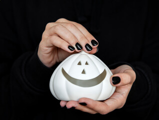Female hands holding funny pumpkins on black background